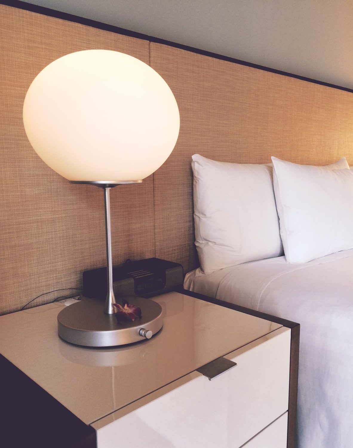 Helles, frisch gemachtes Hotelzimmer mit sauberem Bett und aufgeräumtem Nachttisch